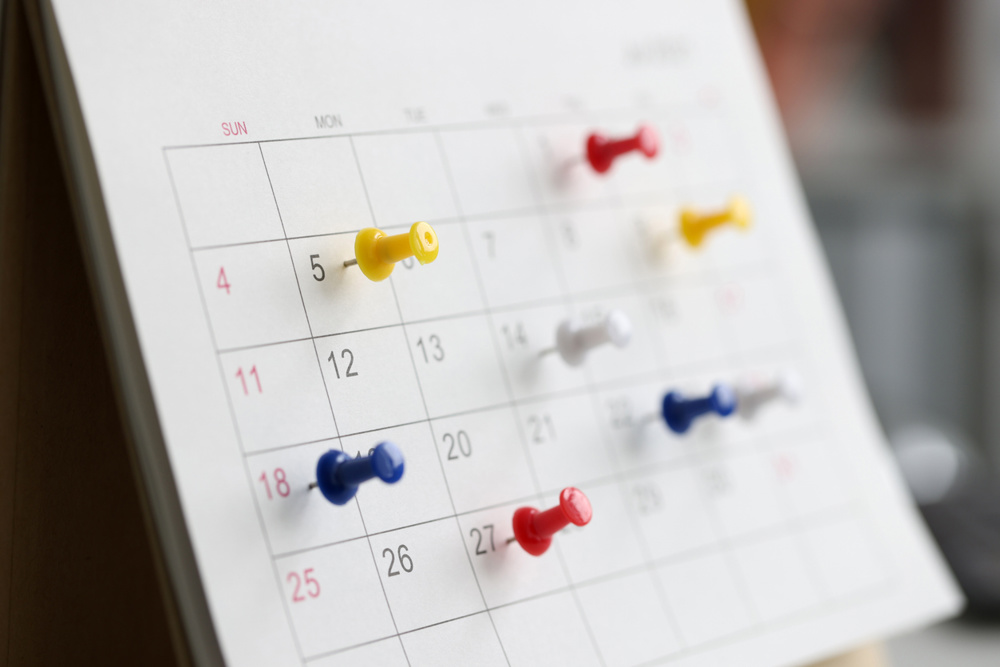Various color thumb tack pins on calendar as reminder. Important business days concept